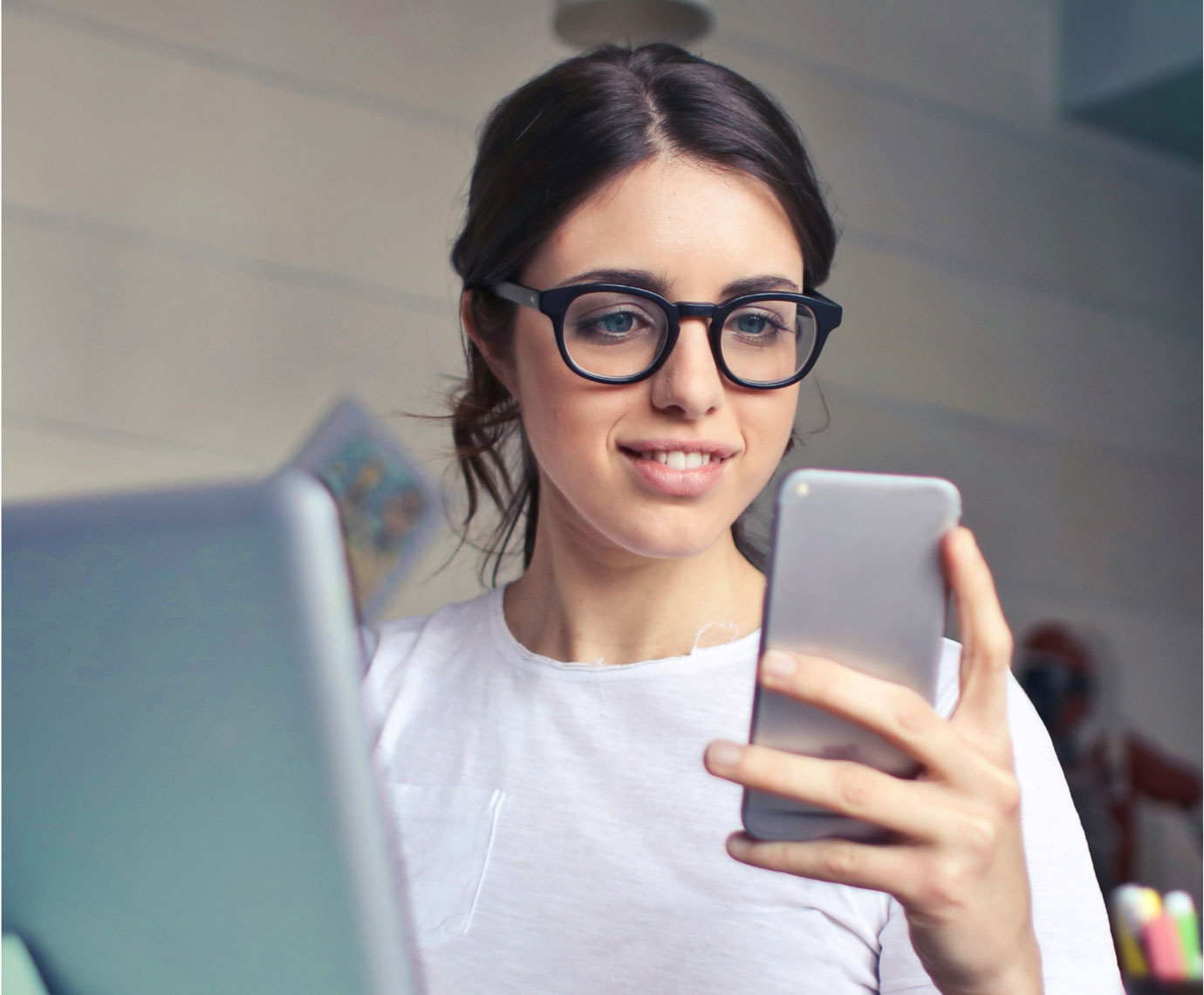 A woman wearing glasses looking at a mobile phone
