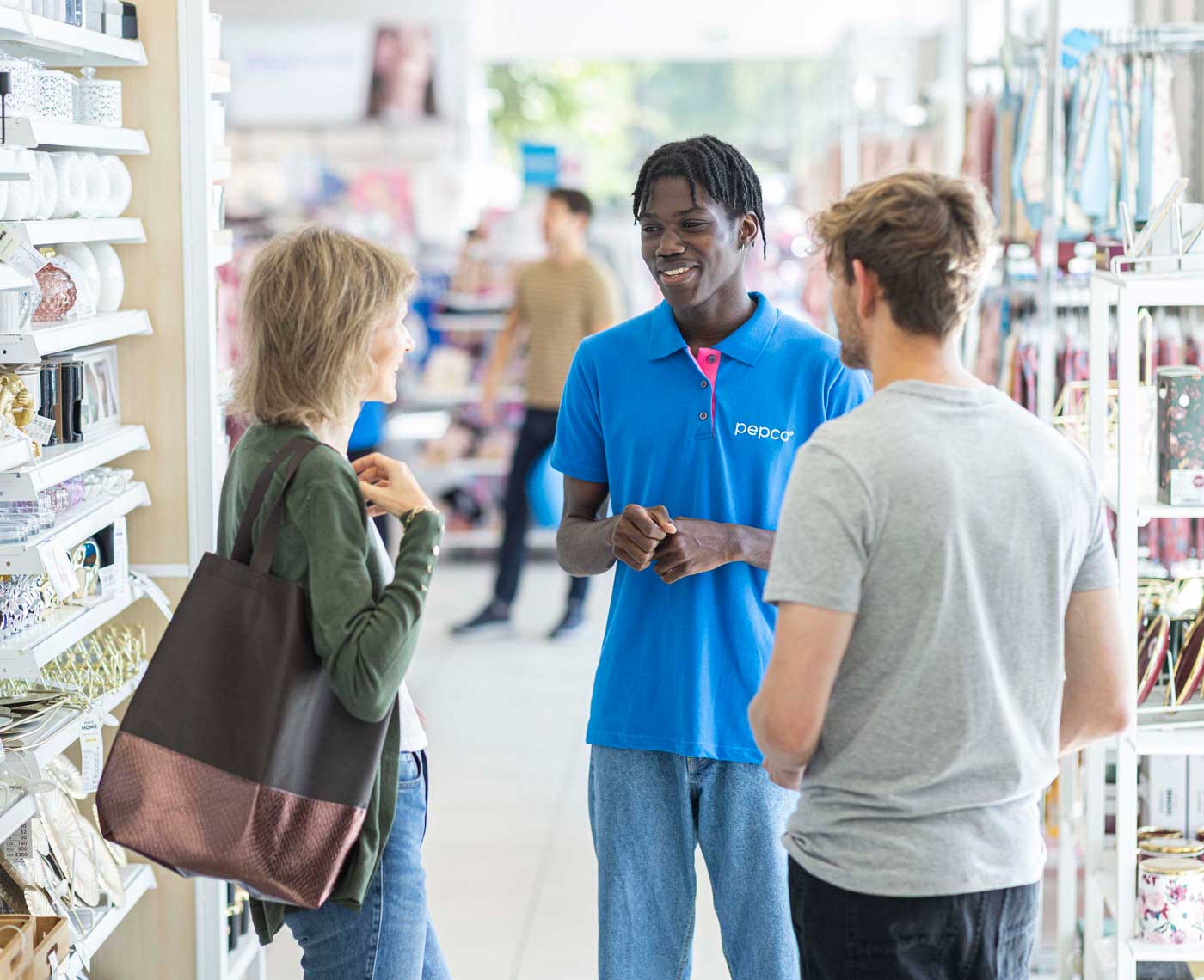 A male employee of Pepco talks to two customers in the isle of a supermarket
