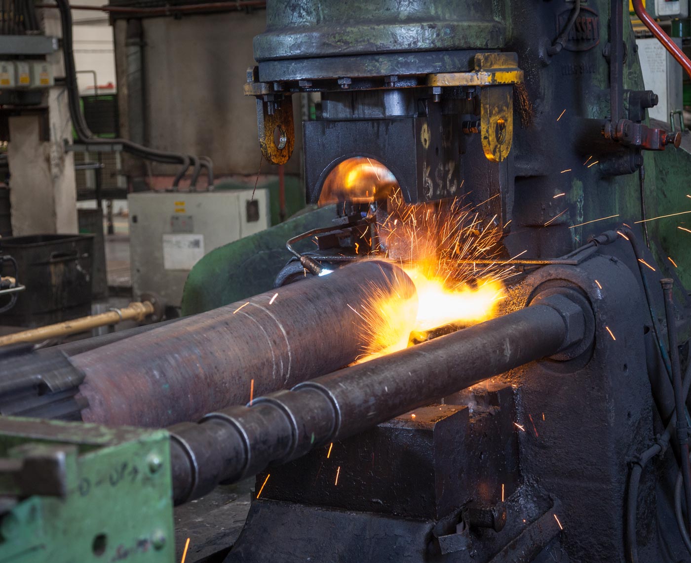 A precision steel cylinder being manufactured at high heat in a factory
