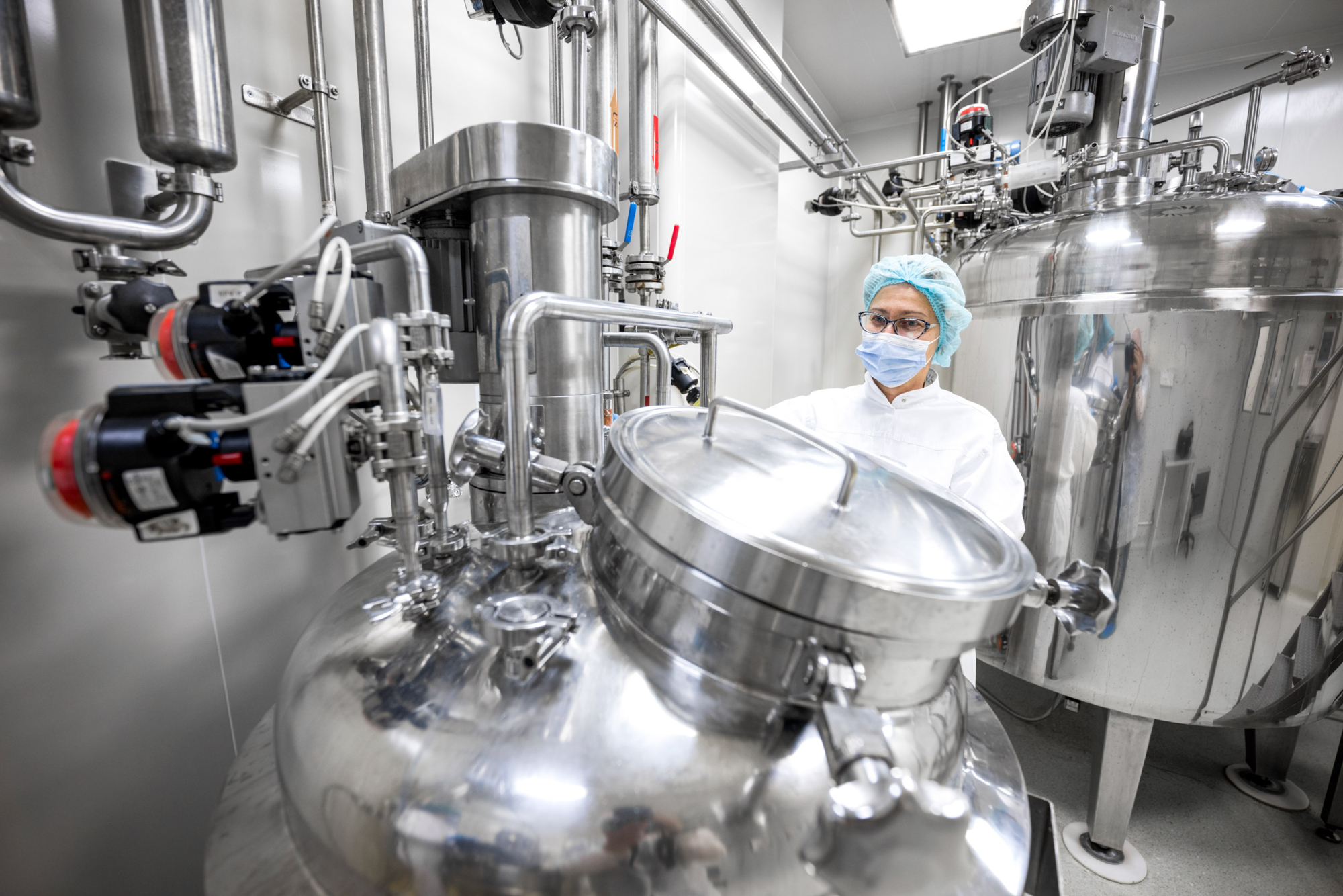 A women wearing laboratory clothing, a hair mask and a face mask in a clinical environment